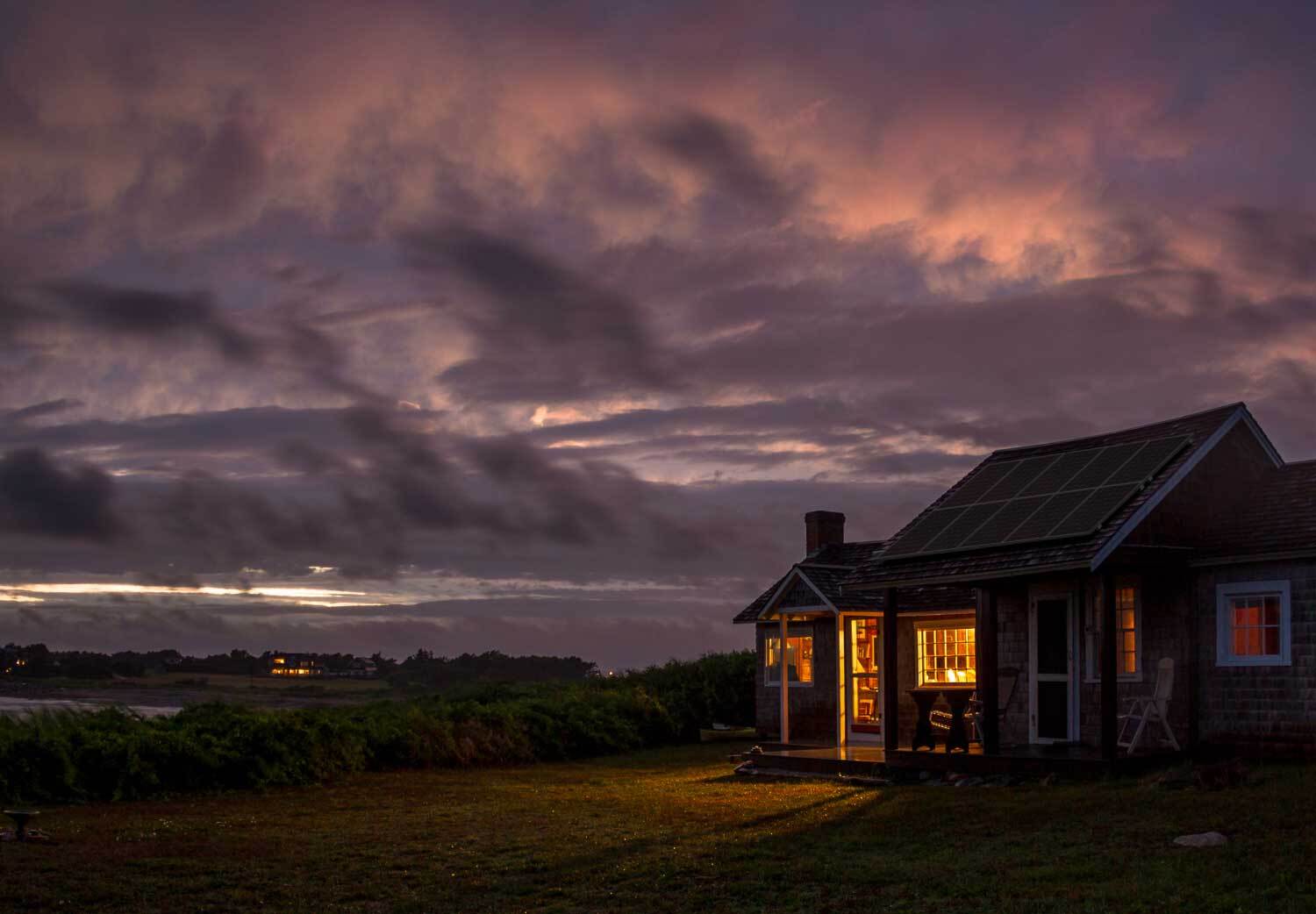 house with porch light o ad stormy sky in background